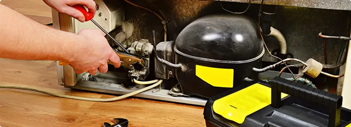 Refrigerator repair technician fixing the compressor and wiring in Getzville, NY