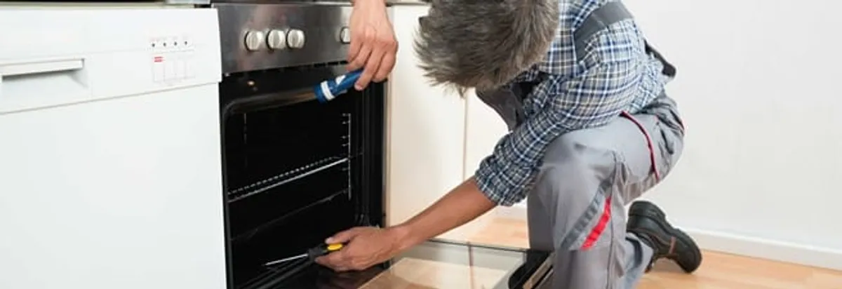 Oven repair technician inspecting and servicing an electric oven in Buffalo, NY