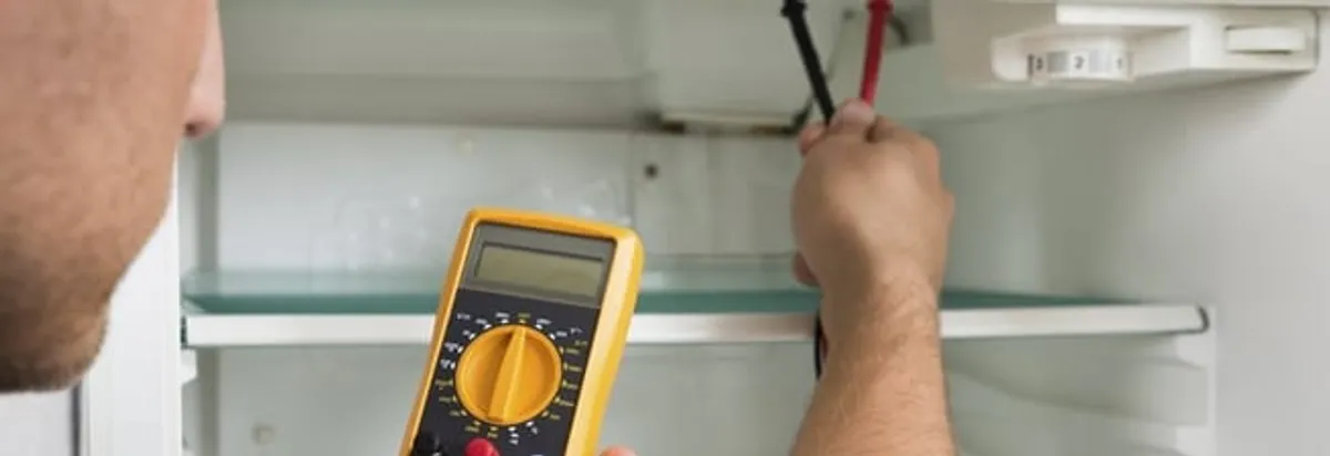 Refrigerator repair technician testing electrical components with a multimeter in Buffalo, NY